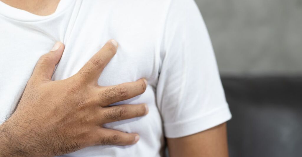 Un uomo che si mette una mano sul petto, in prossimità del cuore