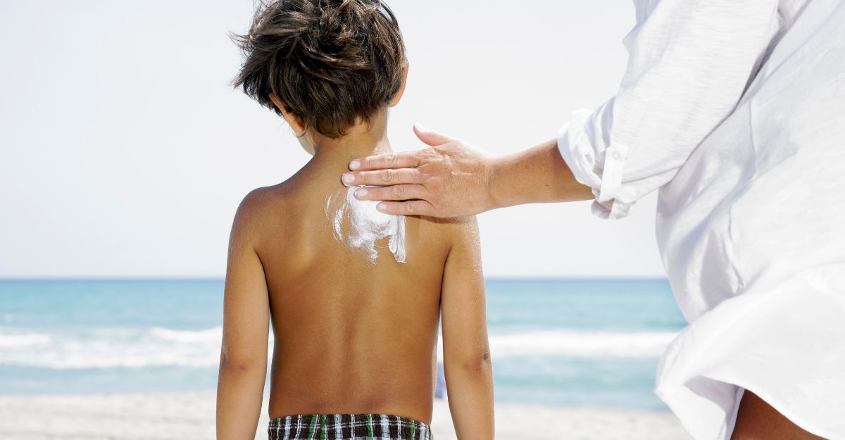 Un genitore che mette la crema solare al figlio in spiaggia