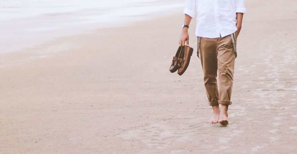 uomo che cammina sulla spiaggia
