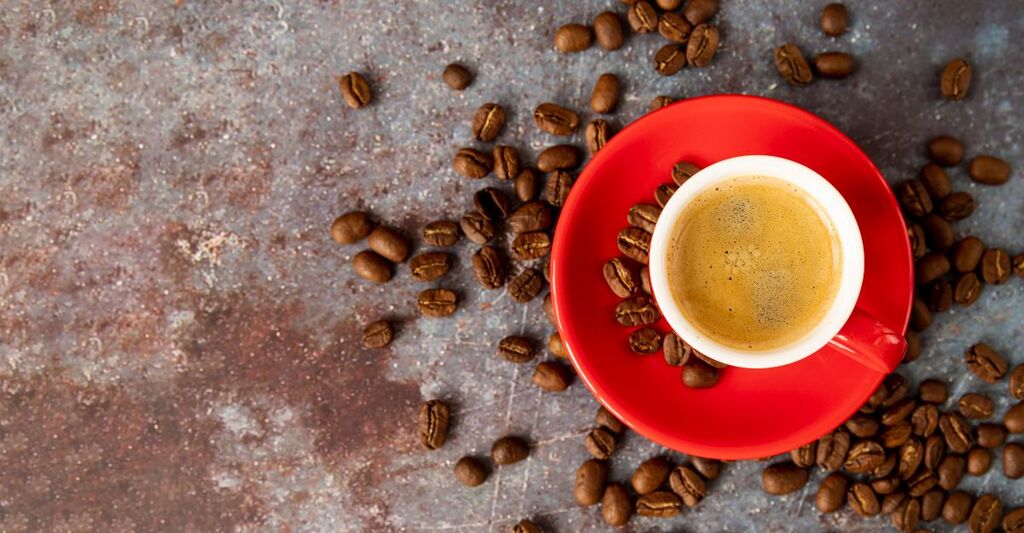 tazzina da caffè sul tavolo, con chicchi di caffè sparsi