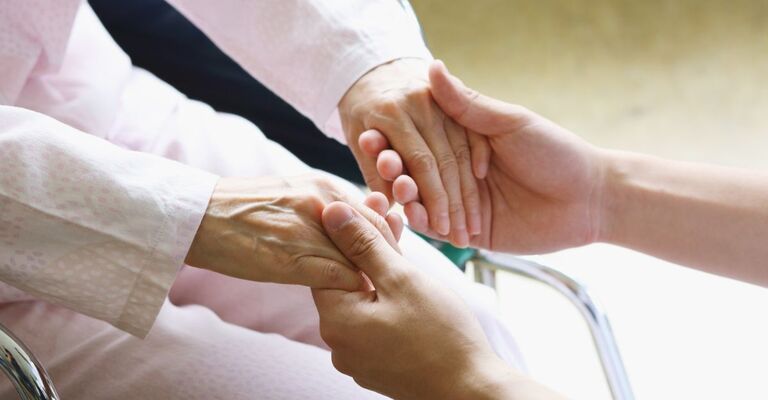 Un medico che tiene le mani di una paziente 