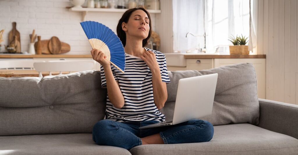 Una signora accaldata che si fa aria con un ventaglio