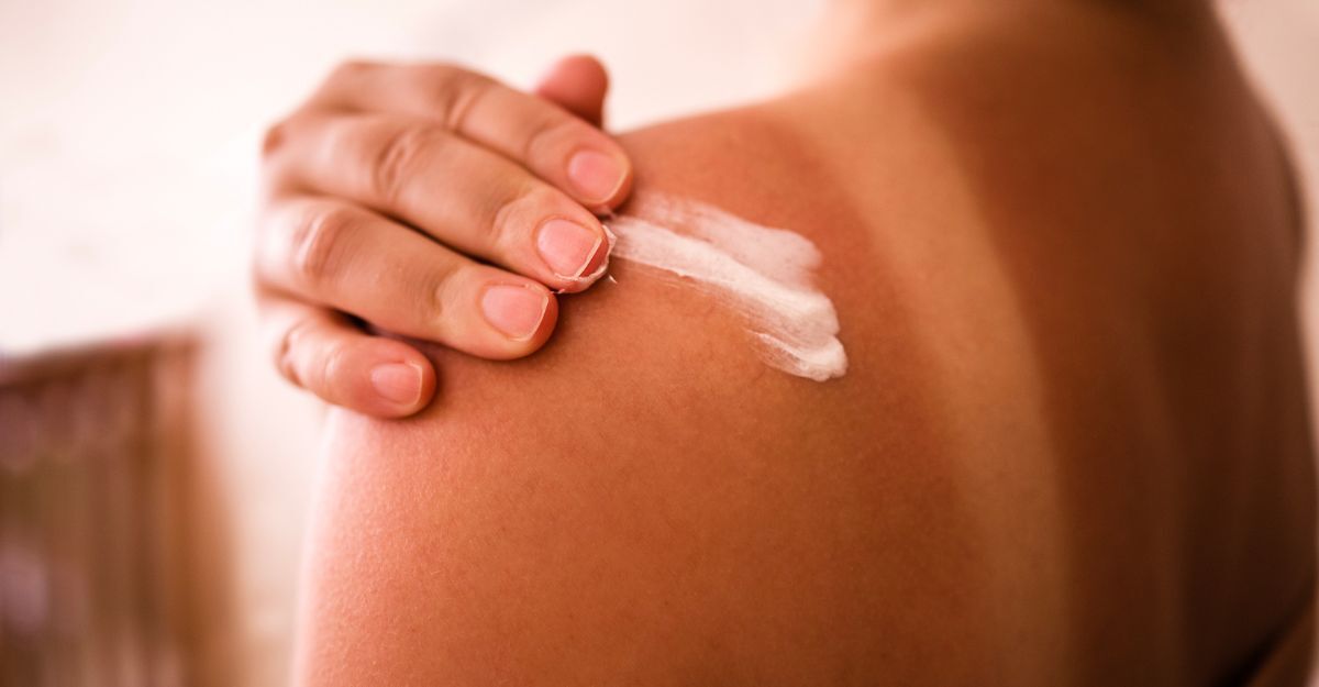 Una ragazza che si spalma della crema sulla schiena abbronzata