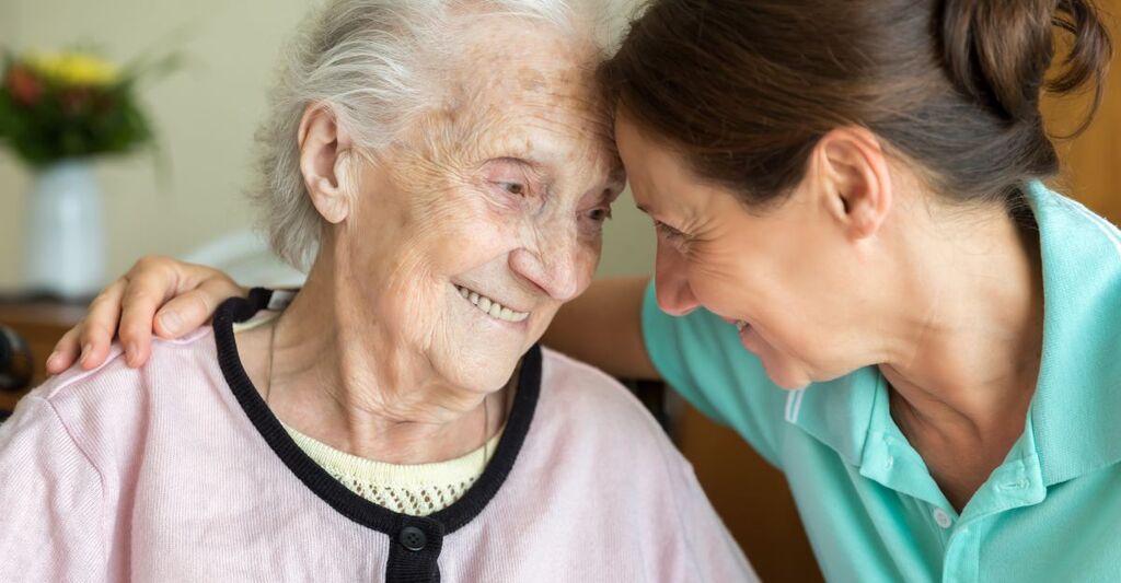 Un'infermiera sorridente con una paziente anziana