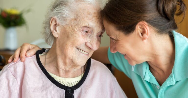 Un'infermiera sorridente con una paziente anziana