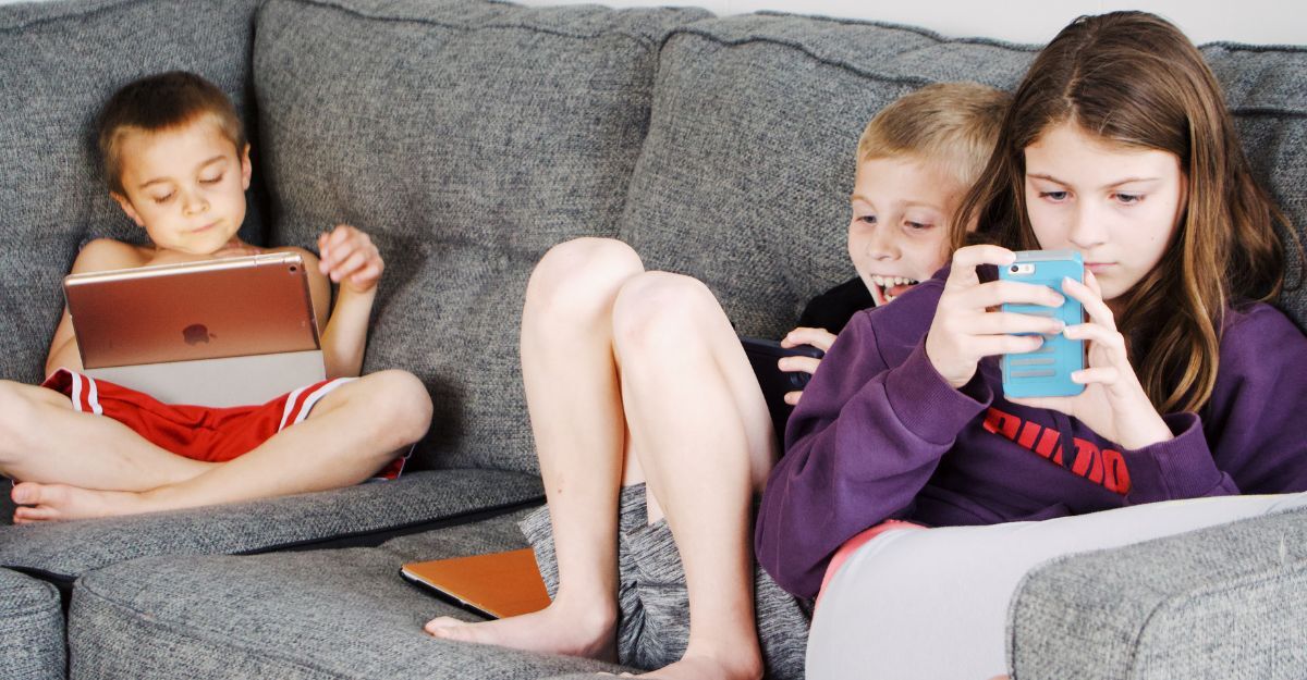 Dei bambini seduti sul divano con tablet e smarthpone