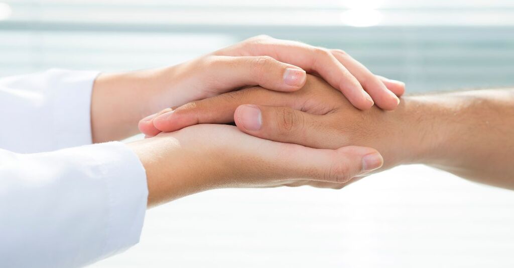 Un medico che tiene le mani di una paziente 
