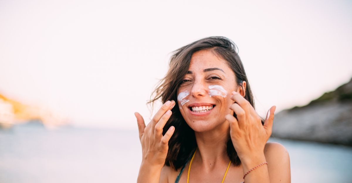 Una ragazza che si spalma la crema solare sulla faccia