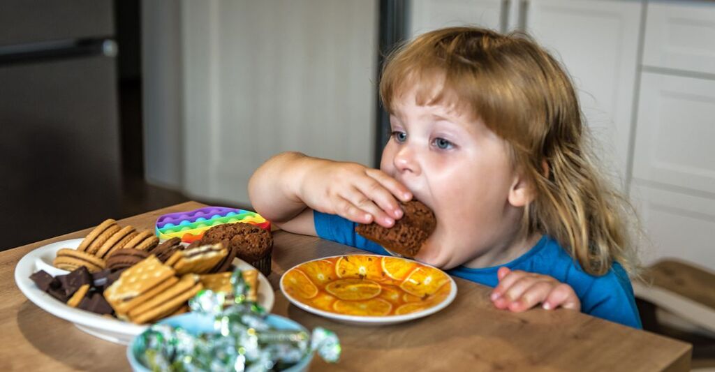 bambina mangia dolci seduta al tavolo