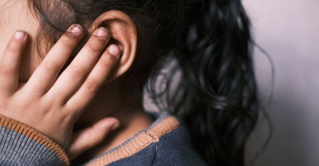 bambina si tocca l'orecchio dolorante
