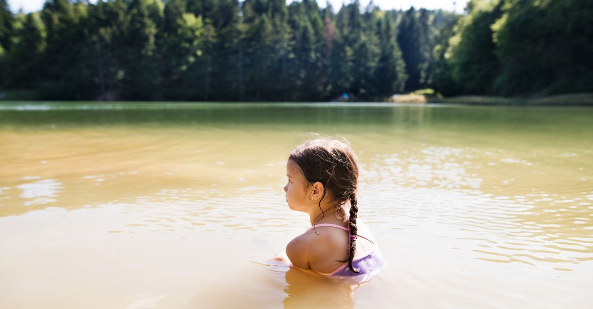 Una bambina che fa il bagno in un lago