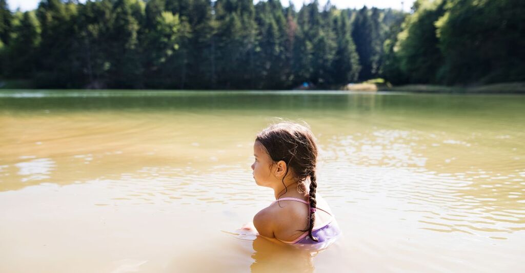 Una bambina che fa il bagno in un lago