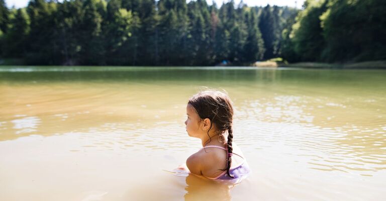 Una bambina che fa il bagno in un lago