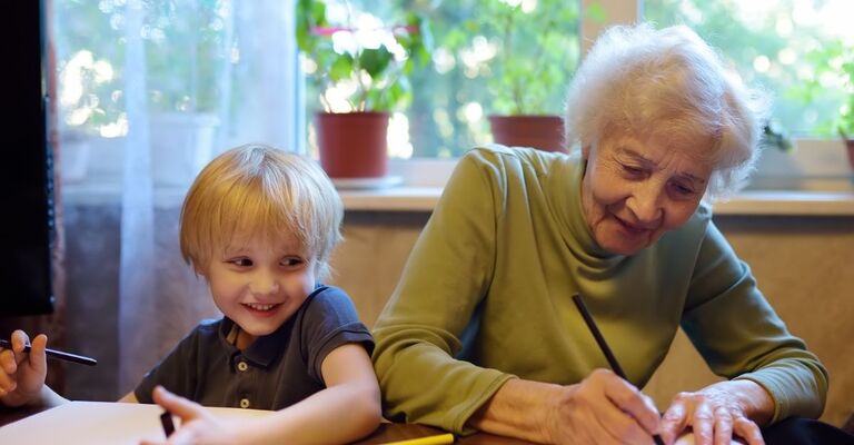 una signora anziana e un bambino disegnano insieme