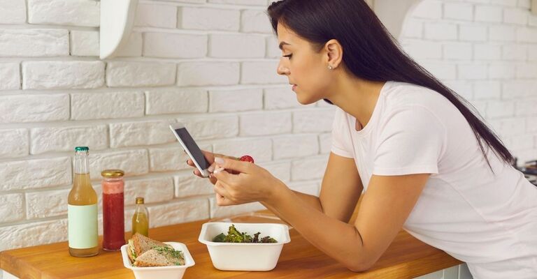 Una ragazza mangia stando al telefono