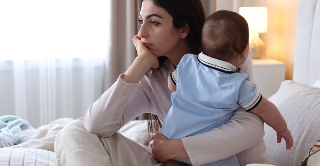 mamma malinconica, con in braccio il suo bambino