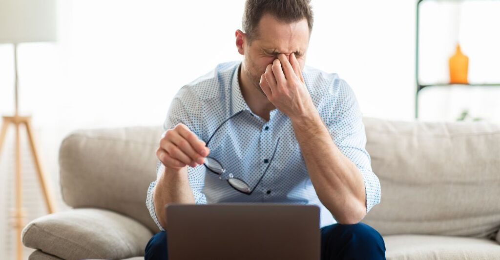 uomo lavora al pc, seduto sul divano