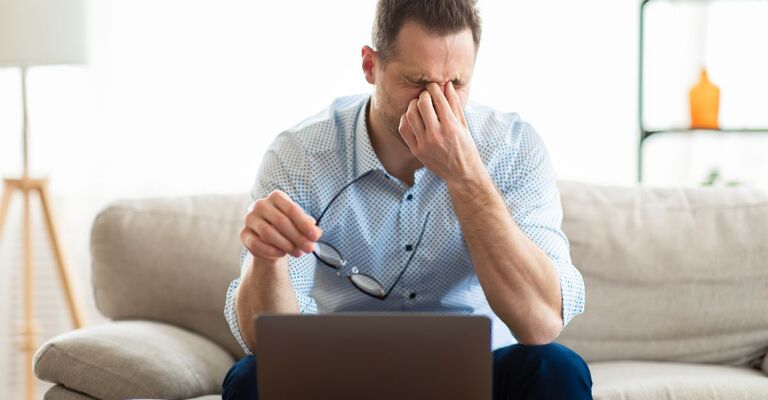 uomo lavora al pc, seduto sul divano