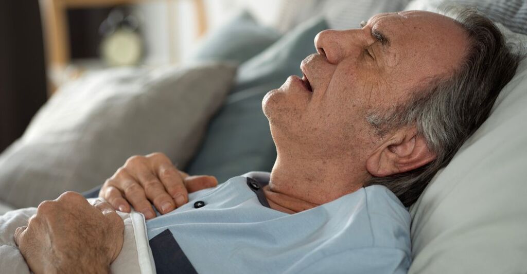 Un signore anziano che dorme con la bocca aperta