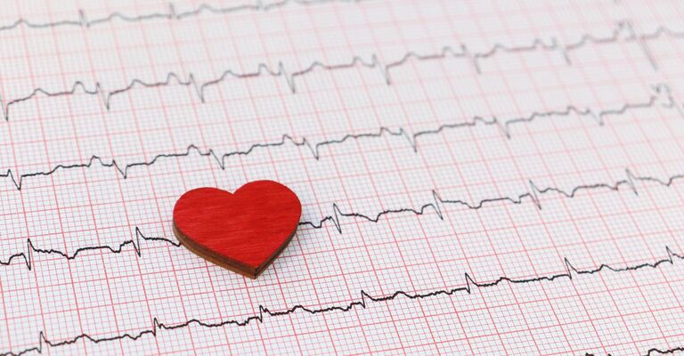 cuore di carta appoggiato sopra ad un tracciato di elettrocardiogramma