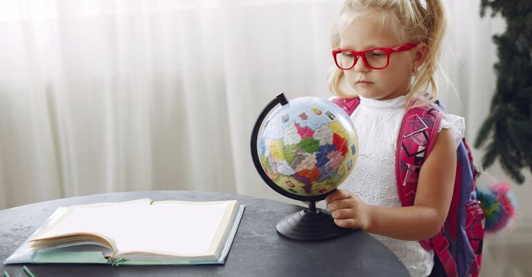 bambina con gli occhiali guarda il mappamondo