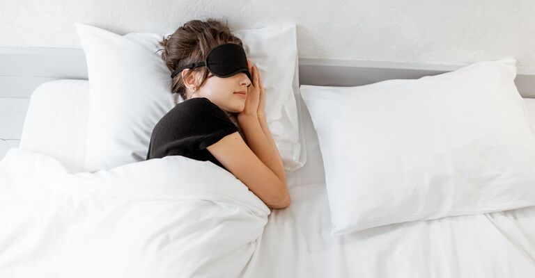 Una ragazza che dorme con la mascherina sugli occhi