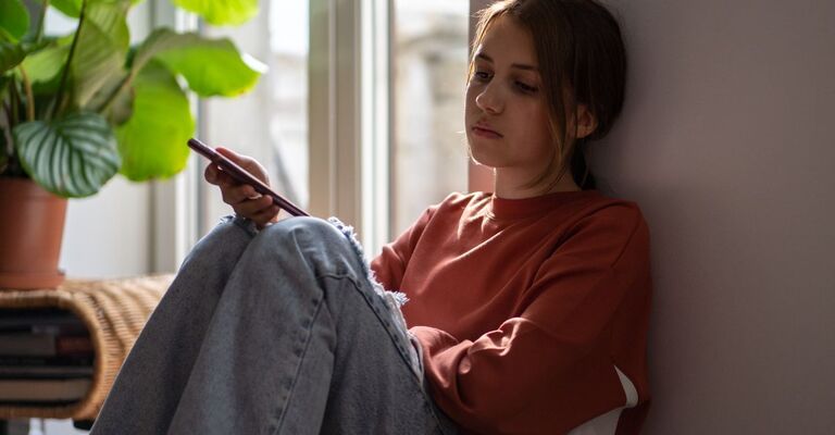 ragazza triste guarda il cellulare