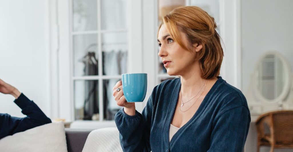 donna seduta sul divano con tazza di tè in mano
