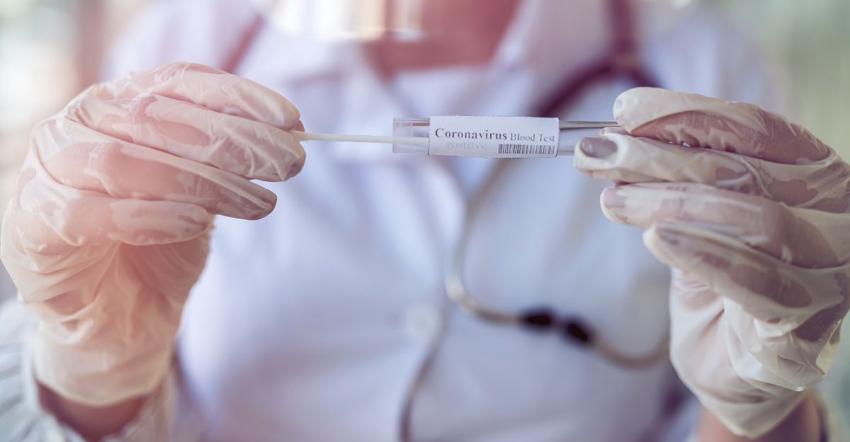 Operatore sanitario con guanti in lattice che mostra una provetta da test con un tampone all'interno