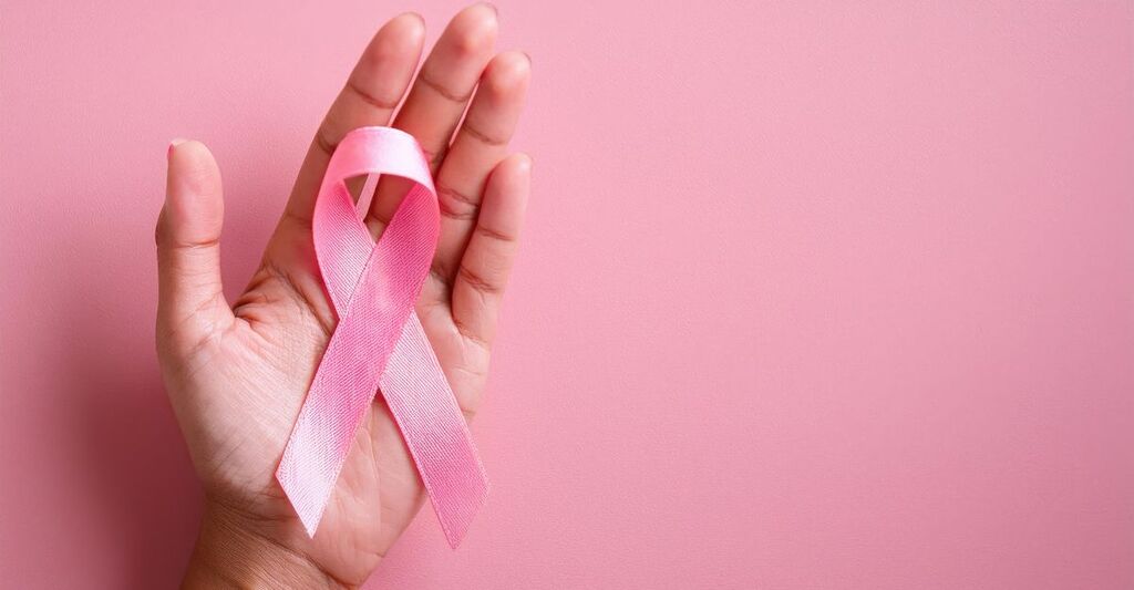 fiocchetto rosa su una mano e sfondo rosa