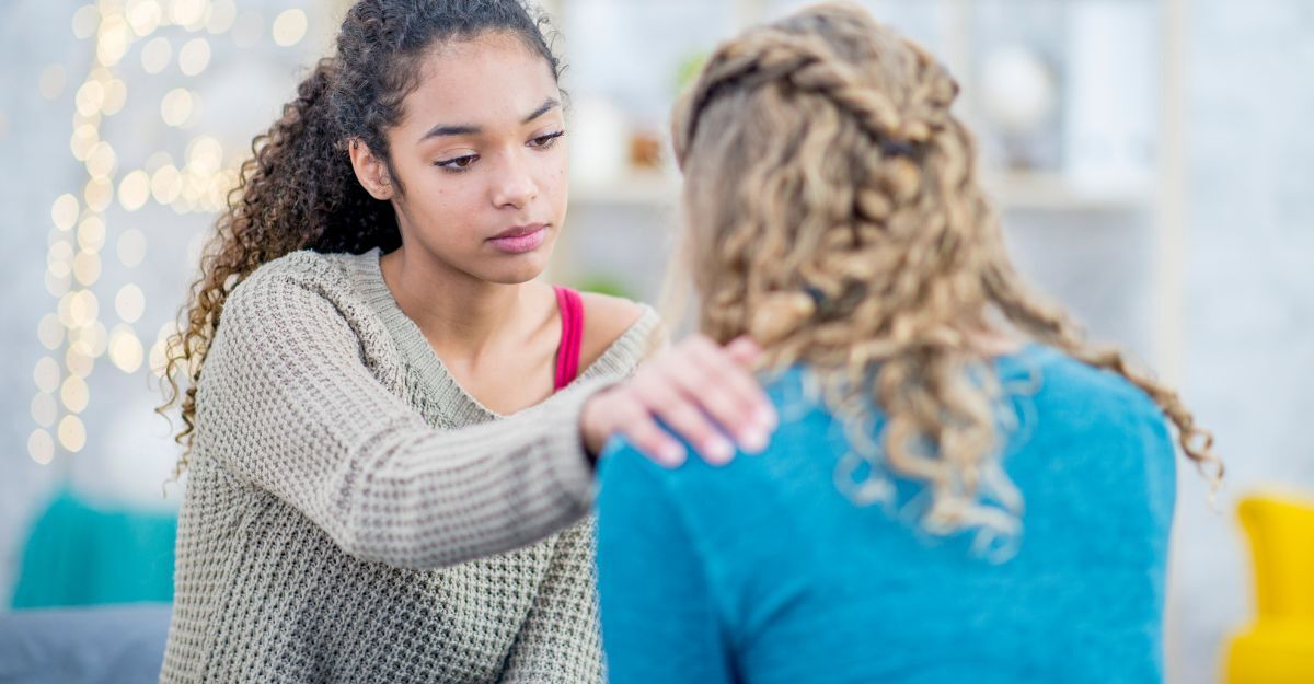 Una ragazza ragazza con un'espressione empatica che consola un'amica mettendole delicatamente una mano sulla spalla