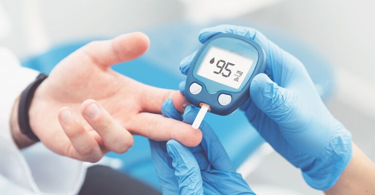 Misurazione della glicemia su un dito con glucometro digitale che indica 95 mg/dL
