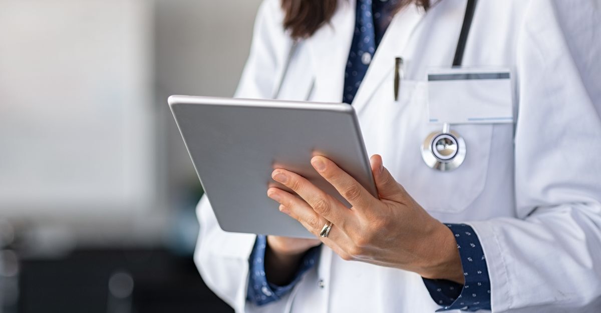 Un medico in camice bianco con uno stetoscopio al collo mentre consulta dei dati su un tablet digitale