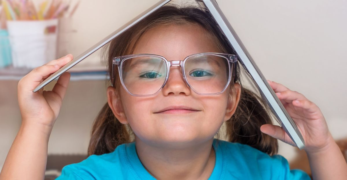 bambina co gli occhiali tiene in testa un libro