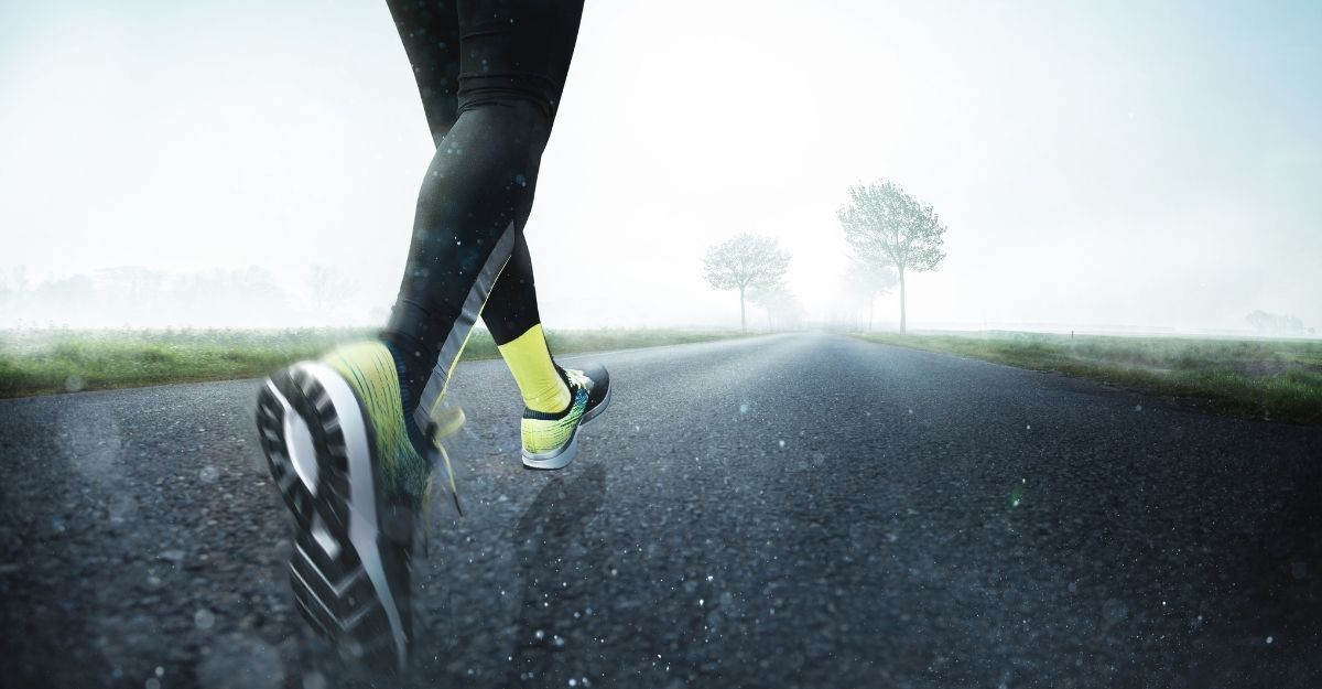 Il primo piano dei piedi di un corridore che corre su un asfalto bagnato