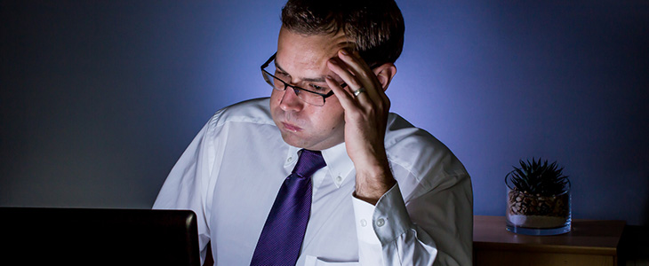 730x300 - Mann sitzt vor Laptop und bl&auml;st Wangen auf