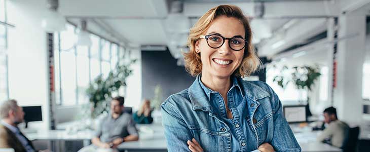 730x300 Frau l&auml;chelnd mit verschr&auml;nkten Armen im Gro&szlig;raumb&uuml;ro