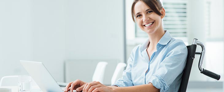 730x300 - Frau im Rollstuhl am Schreibtisch mit Laptop