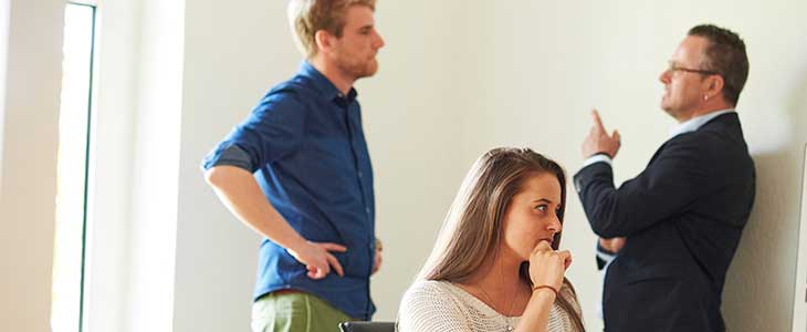 730x200 - 2 Männer stehend im Gespräch - Vordergrund Frau sitzend