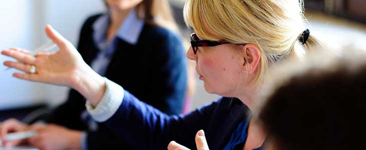 730x300 Frau redet mit Gestik inkl. Personen teilweise sichtbar