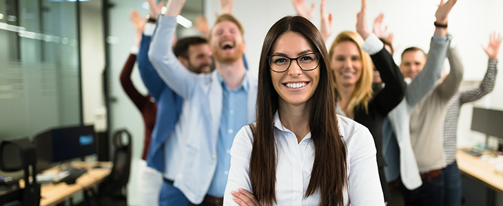 730x300 - Frau im Vordergrund, lachende Personen mit erhobenen H&auml;nden im Hintergrund