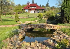 Malownicza willa przytulona do wzgórza ma za tło skarpę porośniętą gęstwiną drzew i krzewów.