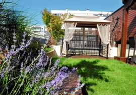 ZACISZNA ALTANKA I SOCZYSTY TRAWNIK to znak firmowy tego tarasu. W altance świetnie się wypoczywa, siedząc na ławce-huśtawce, w cieniu zasłon i rolet.