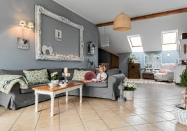 Państwo Monika i Adam zaprosili nas do swojego mieszkania na piętrze rodzinnego domu. Przestronne wnętrze urządzone stylowymi meblami i udekorowane romantycznymi drobiazgami wygląda w świątecznej aranżacji jeszcze piękniej niż na co dzień. <BR /> MIESZKANIE. Wielka rama na ścianie, chociaż bez obrazu, wygląda bardzo dekoracyjnie; świąteczne lampki tylko dodają jej wdzięku. Kiedyś była bordowa i stała na sklepowej wystawie. Mama pani Moniki dojrzała w niej aranżacyjny potencjał i kupiła dla córki. Ciekawą historię ma też stolik kawowy - zanim gospodyni go uratowała, stał w komórce, gdzie służył jako półka na puszki z farbami. Po obcięciu nóg i odnowieniu idealnie pasuje do współczesnej kanapy z IKEA.