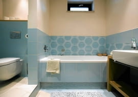 W łazience pełniącej również funkcję toalety warto wydzielić intymną strefę na kącik z sedesem - oczywiście jeśli pozwala na to metraż i kształt pomieszczenia. Można na przykład zbudować ściankę albo zamontować przegrodę z tafli szkła. Wnętrze stanie się wtedy bardziej funkcjonalne.<br/> Łazienkę wykończono w błękicie, - gospodarze uwielbiają ten kolor, a nie pasował do żadnego innego pomieszczenia.