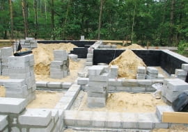 Ściany fundamentowe zwykle wykonuje się z bloczków betonowych. Ich powierzchnie zabezpiecza się masami asfaltowo-kauczukowymi.