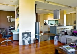 <b> WOKÓŁ KOMINKA. Mąż robi kawę, żona pracuje przy komputerze, dziecko ogląda bajkę. Rodzina jest razem, ale każdy może robić coś innego, nie przeszkadzając reszcie domowników. To efekt umiejętnego podziału przestrzeni dziennej na strefy funkcjonalne. </b> Otwarta część dzienna zajmuje aż dwie trzecie całego mieszkania - niecałe 60 m kw. Urządzono ją tak, by rodzina mogła przebywać razem, mając zapewnione dobre warunki nie tylko do odpoczynku, ale również do pracy. Po połączeniu kuchni z pokojem na środku wnętrza pozostał komin, który został pomysłowo obudowany - powstało tu m.in. miejsce na komputer. Konstrukcja ta umownie wyznacza podział na poszczególne strefy: wypoczynkową, kuchenną i jadalną. Odrębność funkcji podkreśla podłoga ułożona z trzech różnych materiałów (drewno, kamień i płytki gresu). Granicę między kuchnią a kątem wypoczynkowym dodatkowo zaznaczają reflektorki halogenowe zainstalowane w wąskiej długiej wnęce w podwieszanym suficie. <BR /> W aneksie kuchennym zaplanowano wiele schowków ułatwiających utrzymanie porządku: ciąg szafek dolnych i górnych, sięgającą sufitu zabudowę przy bocznej ścianie oraz wyspę z szafką w formie słupa, przesłaniającą zlewozmywak. Do fornirowanych bielonym dębem frontów mebli dobrano kontrastujący blat z granitu. Podłogę w kuchni wyłożono praktycznym gresem.