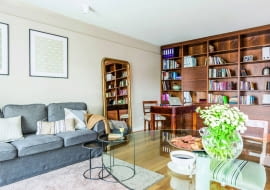 BIBLIOTEKĘ z orzecha amerykańskiego zrobił - według szkiców projektantki - ten sam stolarz, który wykonał kuchenną zabudowę. Żeby przełamać dość monotonny układ półek, w centralnej części umieścił zamykaną szafkę. Na dole znajdują się pojemne szuflady.