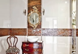 Urządzenia sanitarne w łazienkach stają się coraz mniej widoczne, zwykłe szafki są zastępowane przez komódki. Na plan pierwszy wysuwają się ozdobne wykończenia, dekoracje i dodatki. Bo teraz modne są wnętrza urządzone w wyrazistym stylu.<BR /><b>Inspirowana barokiem.</b> Pani domu bardzo lubi zakupy na pchlich targach, w poszukiwaniu oryginalnych przedmiotów serfuje po internecie. Na aukcji staroci w Szwecji kupiła piękną komódkę oraz lustro w dekoracyjnej ramie. Po krótkim namyśle postanowiła wykorzystać te nabytki w... łazience. Komodę przerobiono na szafkę pod umywalkę, a rama lustra z barokowymi zdobieniami w kształcie kwiatów i liści (podobnie jak uchwyty szafki) stała się motywem przewodnim w aranżacji całego wnętrza ? roślinny wzór można dostrzec również na brązowych płytkach. I tak mimo nowoczesnych elementów piękne stylowe przedmioty narzuciły wnętrzu pałacowy styl. <BR />WNĘTRZA - ŁAZIENKI. Mimo sentymentu do staroci gospodarze nie uciekają od nowoczesności. W podwieszonym suficie zamontowano głośniki połączone z centralnym systemem audio w mieszkaniu.