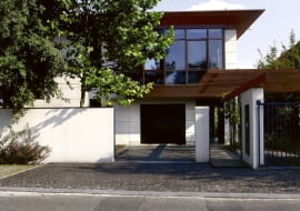 Widok na dom od strony ulicy. Za przeszklonymi ścianami na piętrze zaplanowano pracownię plastyczną. Drugi podobny szklany kubik od strony skarpy mieści jadalnię